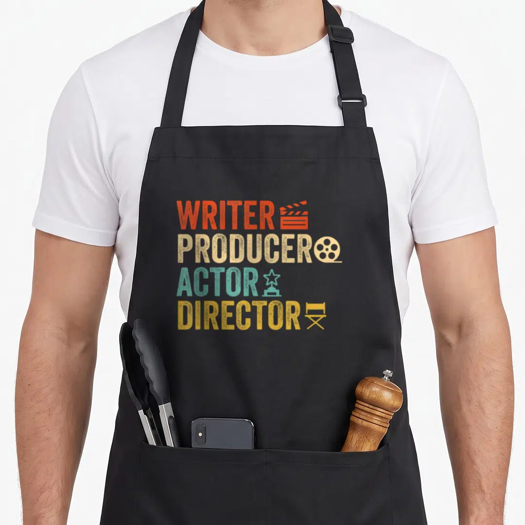 Writer acting apron - Stacked Writer Producer Actor Director text with film icons in orange beige teal and yellow — shown on a black cotton canvas apron against a white background