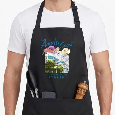 Amalfi italian apron - Blue Amalfi Coast script over pink flowers and watercolor cliff town with Costiera Amalfitana — shown on a black cotton canvas apron against a white background