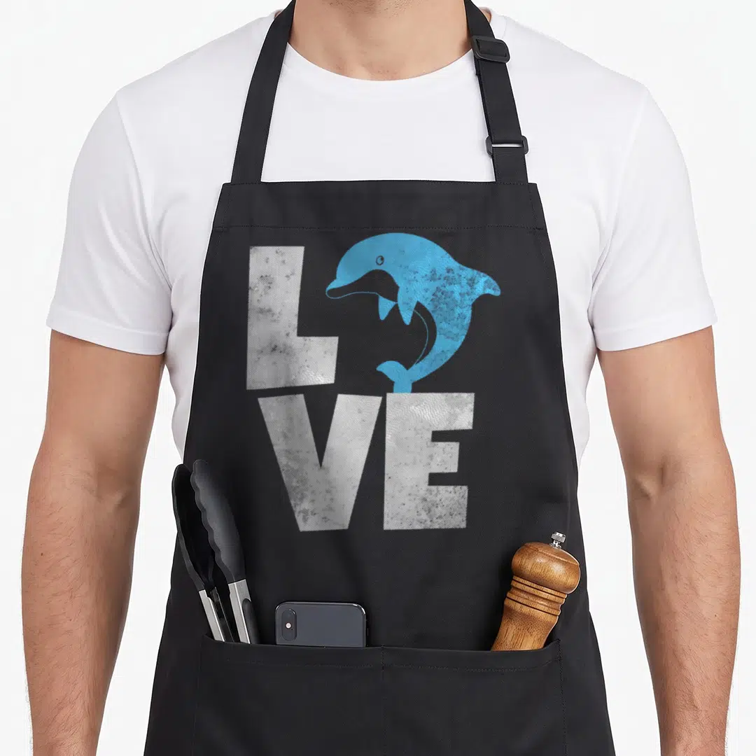 Dolphin animal apron - Blue dolphin replacing O in white LOVE text — shown on a black cotton canvas apron against a white background