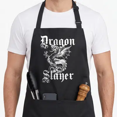 Slayer renaissance apron - White gothic Dragon Slayer text surrounding a central white line-art dragon illustration — shown on a black cotton canvas apron against a white background