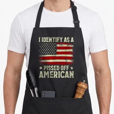 Pissed american flag apron - Distressed USA flag with I IDENTIFY AS A PISSED OFF AMERICAN text and two stars — shown on a black cotton canvas apron against a white background