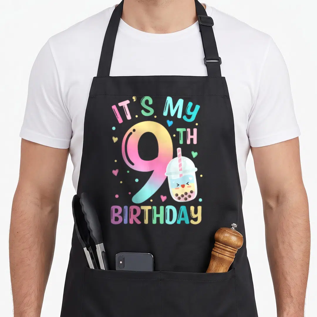 9th tea party aprons - Cartoon bubble tea cup next to gradient number 9 and colorful text celebrating a ninth birthday — shown on a black cotton canvas apron against a white background