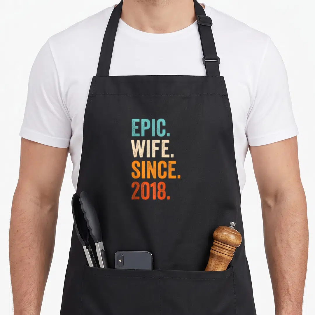 Wife wedding aprons - Stacked retro text EPIC WIFE SINCE 2018 in blue beige orange and red — shown on a black cotton canvas apron against a white background
