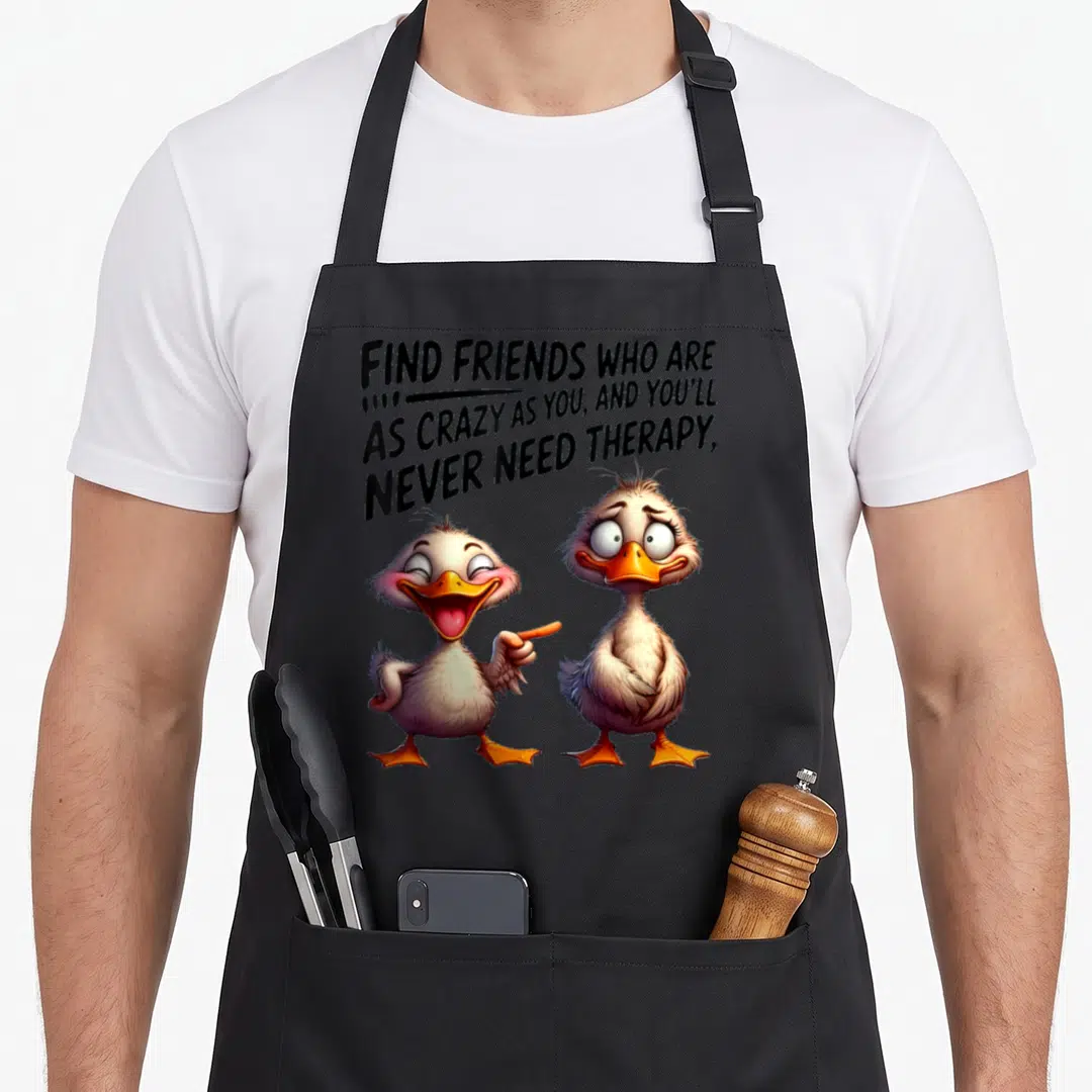 Duck find aprons - Two cartoon ducks below text about crazy friends and therapy on a black apron — shown on a black cotton canvas apron against a white background