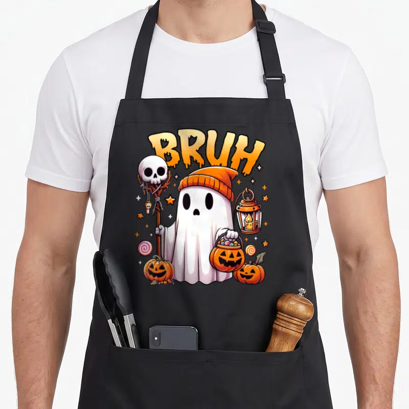 Bruh halloween apron - Cartoon ghost in orange beanie holds skull staff and pumpkin candy bucket under BRUH text — shown on a black cotton canvas apron against a white background