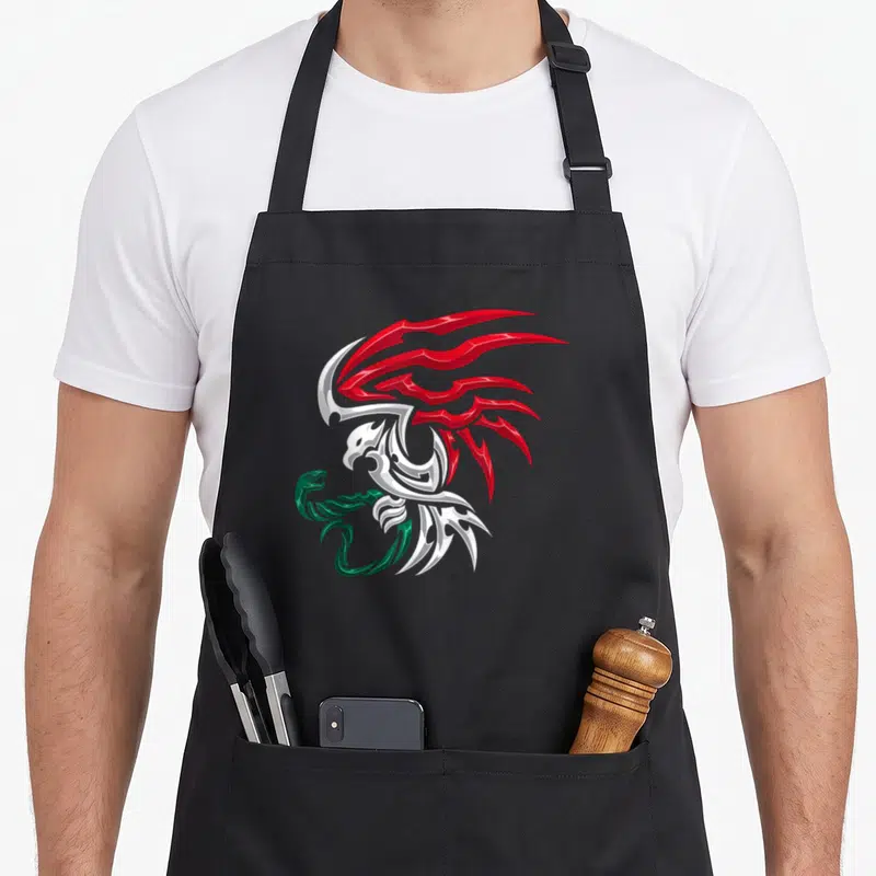 Coat mexico apron - Stylized eagle in green white red metallic tribal design on black apron front panel — shown on a black cotton canvas apron against a white background
