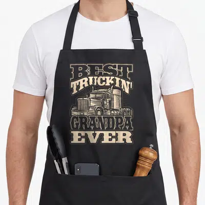 Truckin grandpa semi truck apron - Retro beige and brown semi-truck illustration with BEST TRUCKIN GRANDPA EVER text — shown on a black cotton canvas apron against a white background