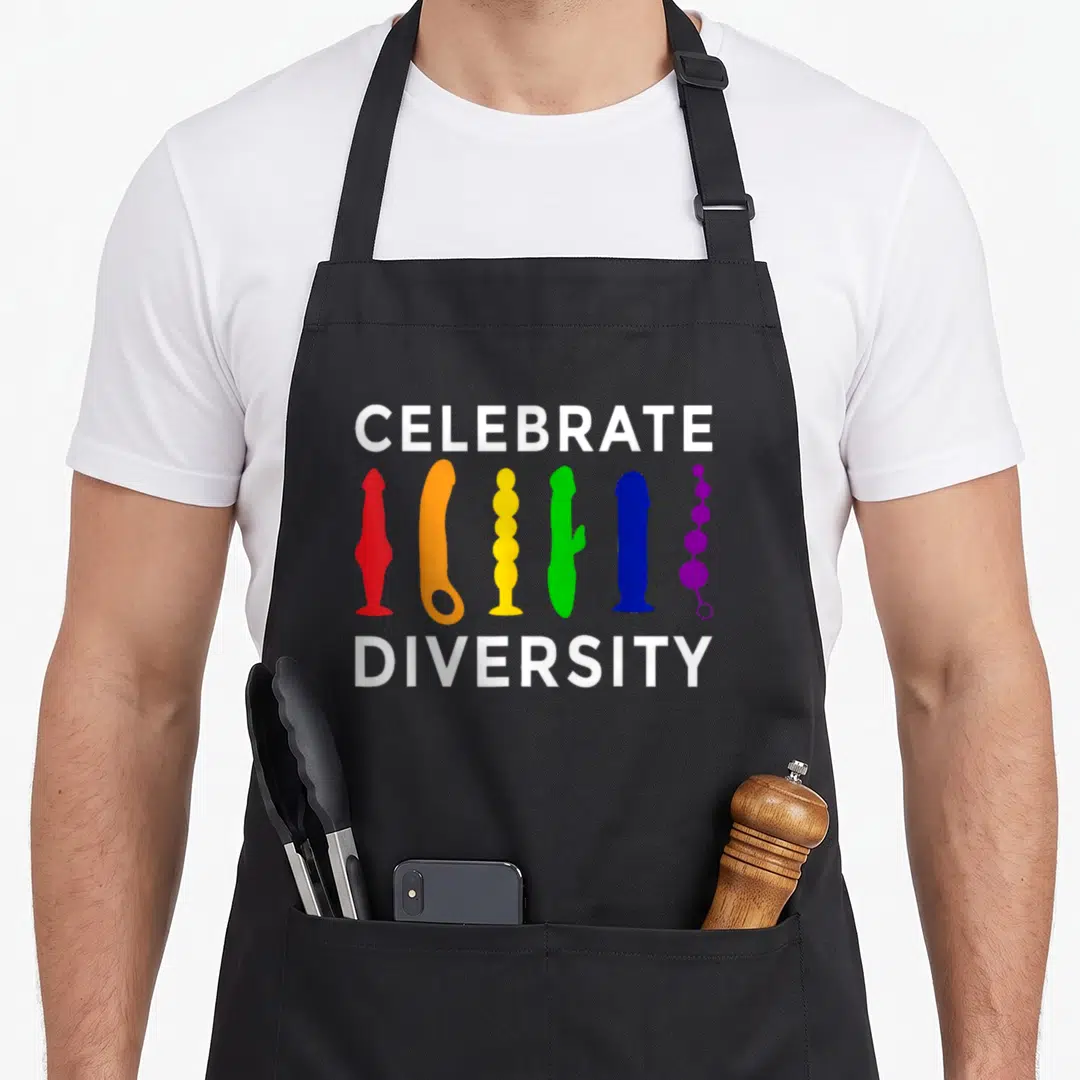 Celebrate pride apron - Six colorful dildo silhouettes between white Celebrate Diversity text on black fabric — shown on a black cotton canvas apron against a white background