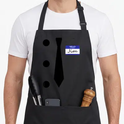 Hole halloween apron - Black necktie, three circular holes, and blue white Jim name tag — shown on a black cotton canvas apron against a white background