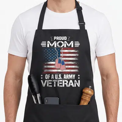 Army family aprons - Distressed USA flag with dog tags and text Proud Mom of a U.S. Army Veteran — shown on a black cotton canvas apron against a white background
