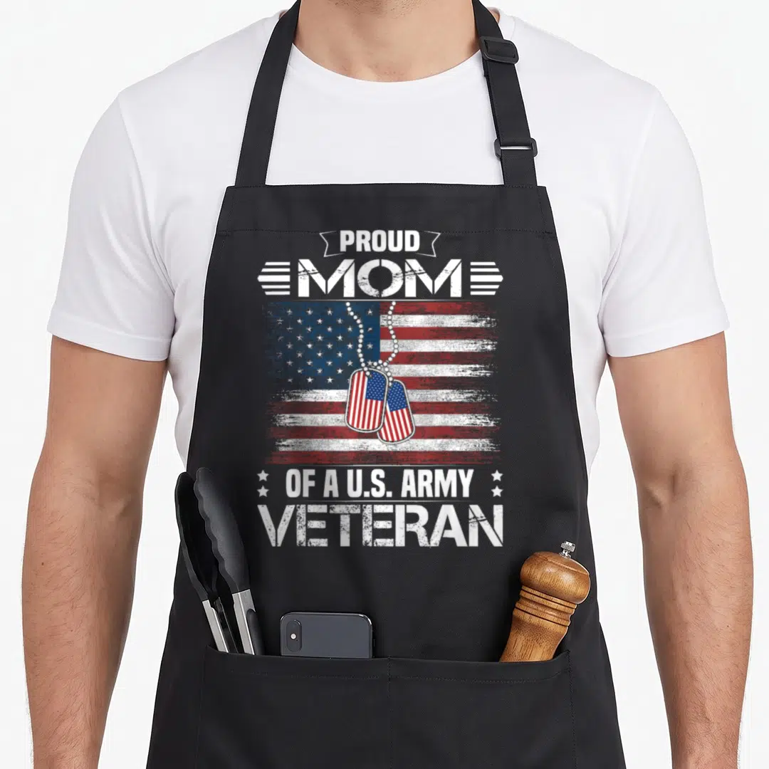 Army family aprons - Distressed USA flag with dog tags and text Proud Mom of a U.S. Army Veteran — shown on a black cotton canvas apron against a white background