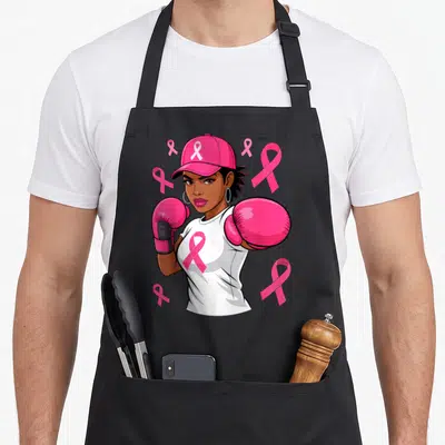 African ribbon apron - Cartoon woman with pink cap, boxing gloves, white shirt with pink ribbon, and floating pink — shown on a black cotton canvas apron against a white background