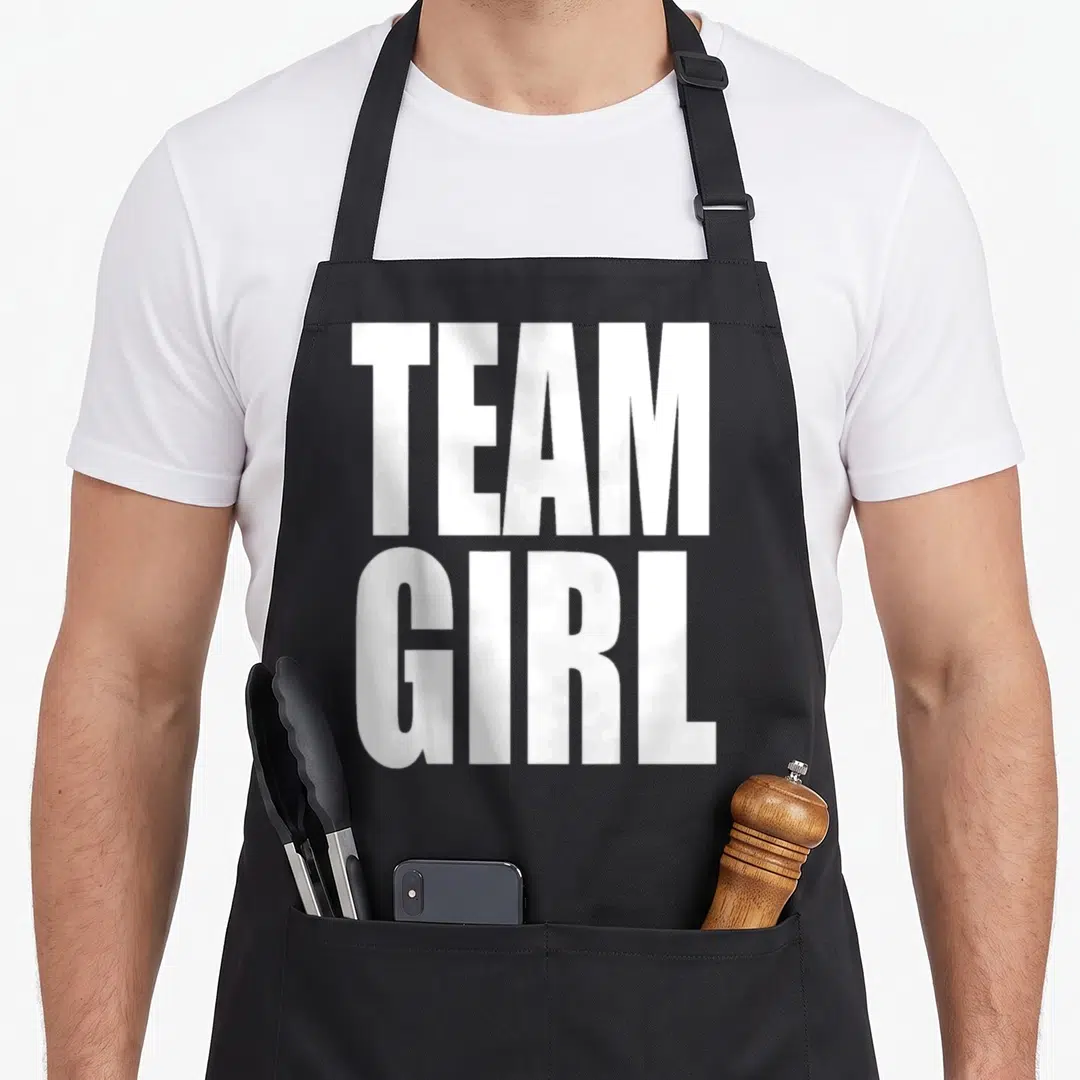 Baby pregnant squad apron - Stacked white TEAM GIRL text in bold sans-serif font — shown on a black cotton canvas apron against a white background