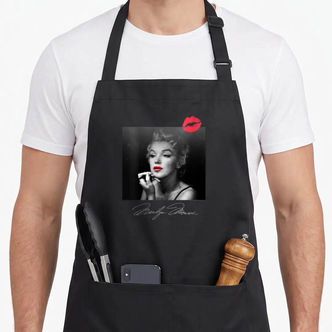 Room marilyn monroe apron - Grayscale Marilyn Monroe photo with red lipstick kiss and script name below — shown on a black cotton canvas apron against a white background