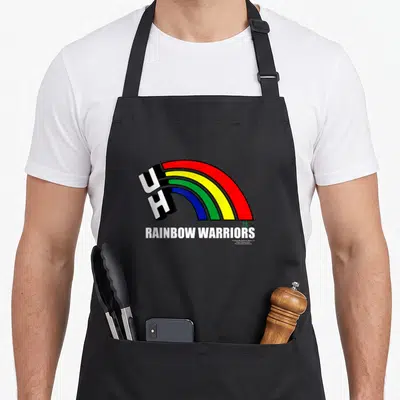 University rainbow apron - UH block letters with arching rainbow and RAINBOW WARRIORS text below — shown on a black cotton canvas apron against a white background