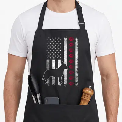 Heeler american flag apron - Distressed US flag with white dog outline and vertical red paw prints on black fabric — shown on a black cotton canvas apron against a white background