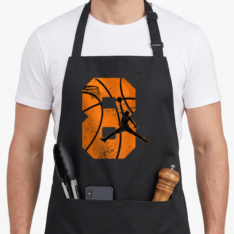 Bday 8yr birthday apron - Orange number 8 basketball shape with black jumping player silhouette in distressed style — shown on a black cotton canvas apron against a white background