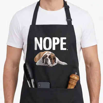 Vintage saint dog apron - NOPE. text above lying Saint Bernard in white brown and black — shown on a black cotton canvas apron against a white background
