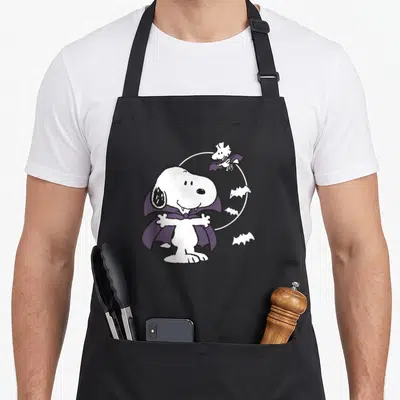Funny vampire halloween apron - Snoopy vampire with purple cape, white moon, Woodstock as bat, cartoon style — shown on a black cotton canvas apron against a white background