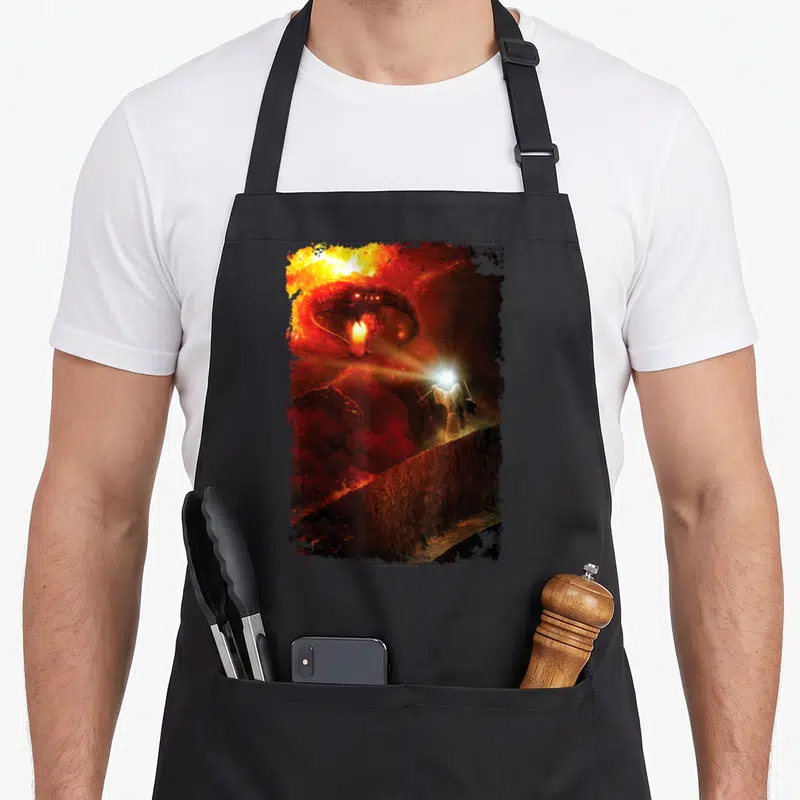Shall ring apron - Giant red demon head looming over small person holding light on a wall — shown on a black cotton canvas apron against a white background