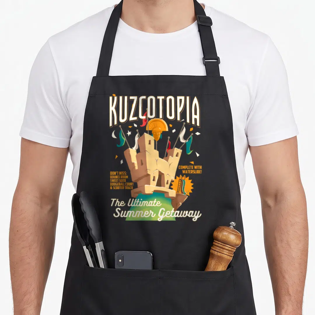 Groove emperor penguin apron - Kuzcotopia sandcastle with flags and listed resort amenities like bounce room — shown on a black cotton canvas apron against a white background