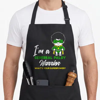 Warrior cerebral palsy awareness apron - Cartoon superhero child with green mask and text I'm a Cerebral Palsy Warrior — shown on a black cotton canvas apron against a white background