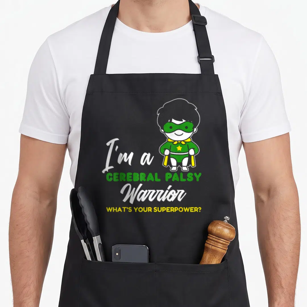 Warrior cerebral palsy awareness apron - Cartoon superhero child with green mask and text I'm a Cerebral Palsy Warrior — shown on a black cotton canvas apron against a white background