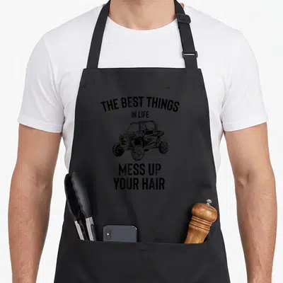 Sxs hair apron - Black UTV illustration with text THE BEST THINGS IN LIFE MESS UP YOUR HAIR — shown on a black cotton canvas apron against a white background