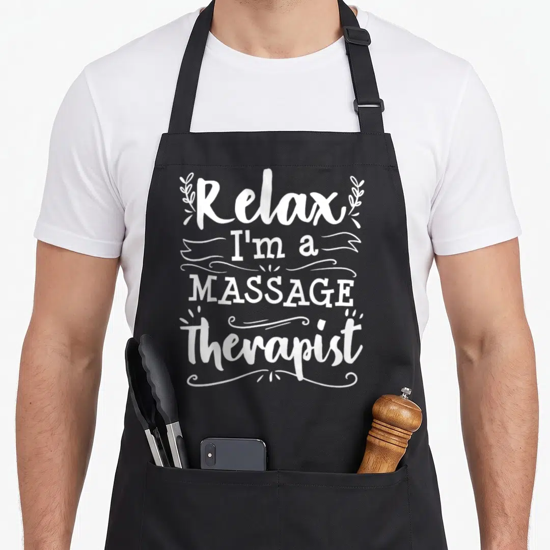 Therapist masseuse massage therapy apron - White stacked text Relax I'm a MASSAGE Therapist with leafy branches — shown on a black cotton canvas apron against a white background
