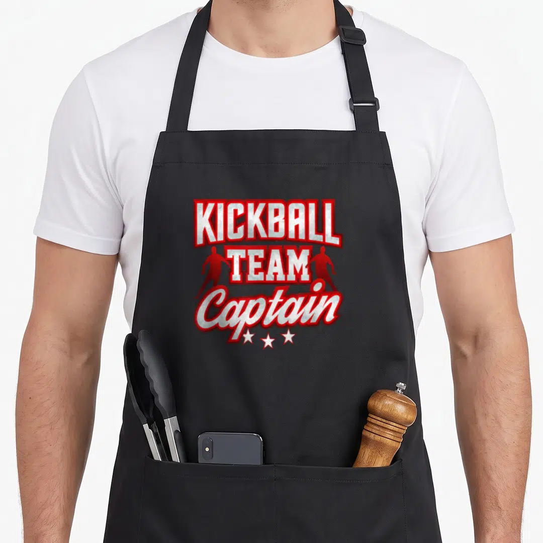 Kickball team captain apron - Red and white KICKBALL TEAM Captain text with player silhouettes and three stars — shown on a black cotton canvas apron against a white background