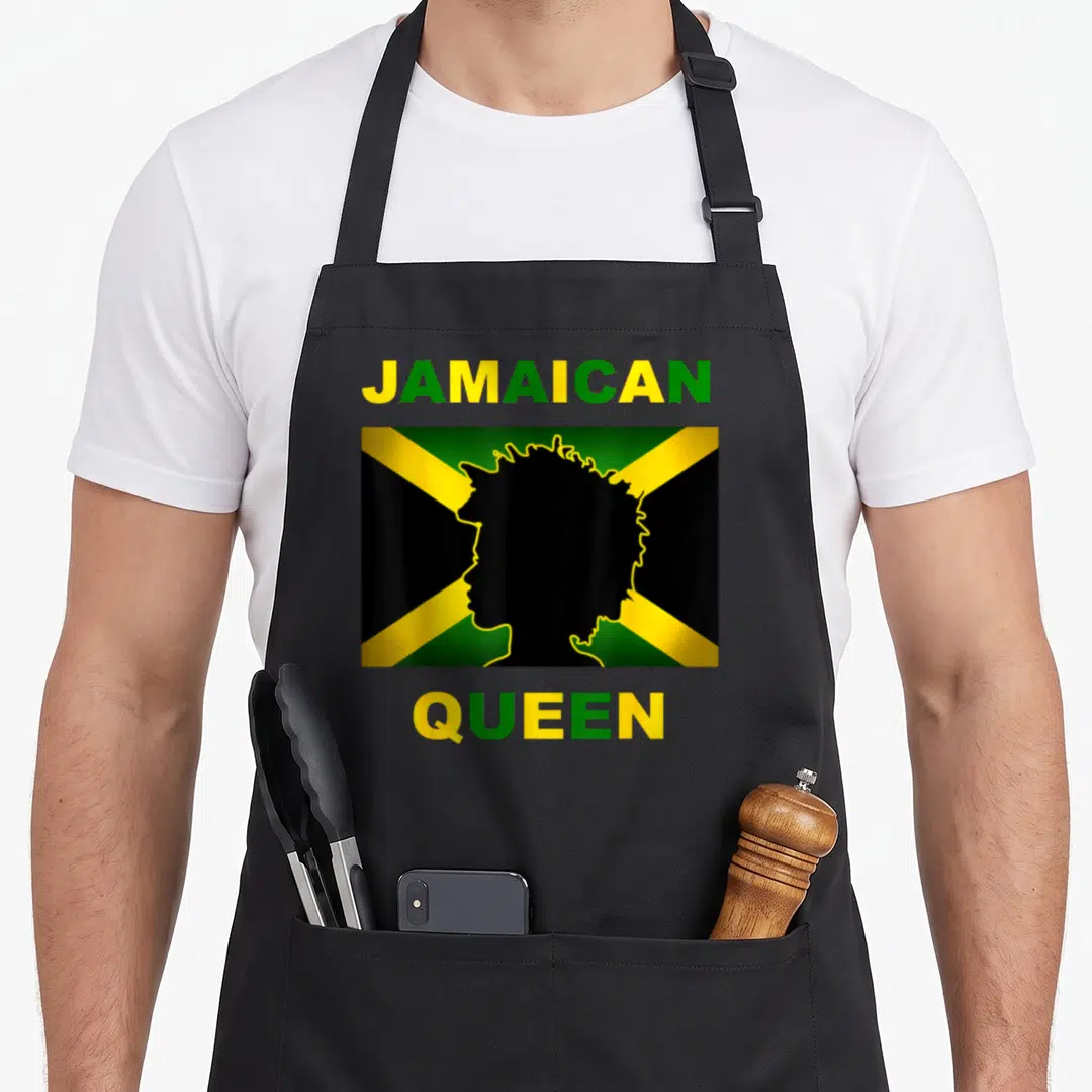 Independent queen apron - Jamaican flag rectangle with black woman silhouette and stacked JAMAICAN QUEEN text in green — shown on a black cotton canvas apron against a white background