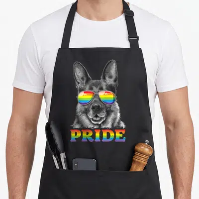 Shepherd gay pride apron - Grayscale German Shepherd head wearing rainbow aviator sunglasses above rainbow PRIDE text — shown on a black cotton canvas apron against a white background