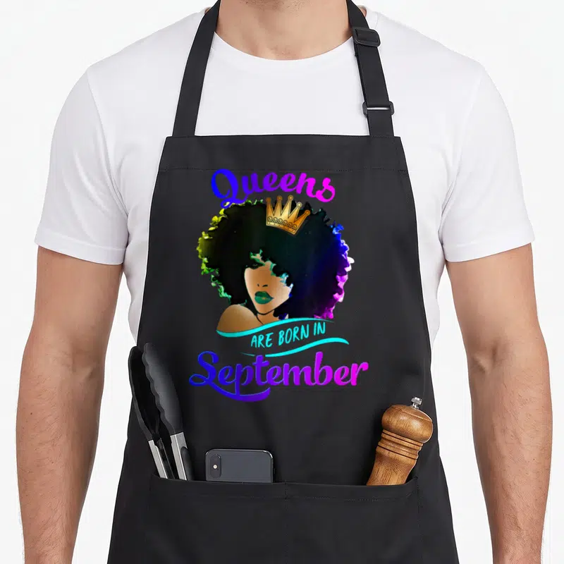 Virgo birthday apron - Crowned woman with afro and text Queens Are Born In September — shown on a black cotton canvas apron against a white background