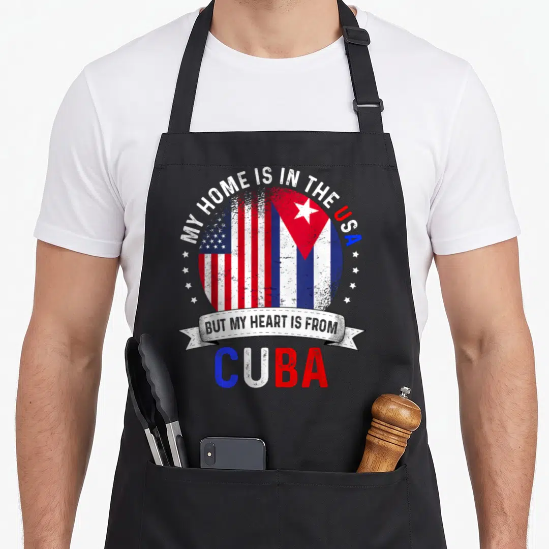 Cuba patriots apron - Distressed combined US and Cuba flag circle with arched text and ribbon banner reading MY HOME IS — shown on a black cotton canvas apron against a white background