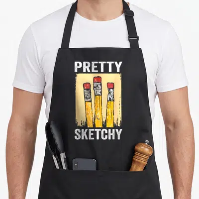 Pretty paint apron - PRETTY SKETCHY text above three yellow pencils with red erasers in cartoon style — shown on a black cotton canvas apron against a white background