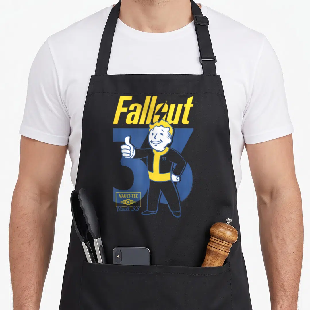 Vault show apron - Vault Boy giving thumbs up in front of blue 33 with Fallout header and Vault 33 logo — shown on a black cotton canvas apron against a white background