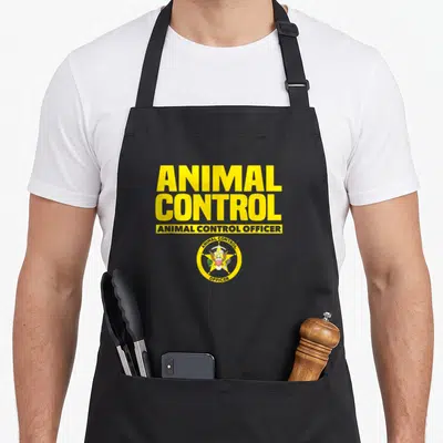 Public safety apron - Yellow ANIMAL CONTROL text above circular badge with eagle star in red blue white yellow on black — shown on a black cotton canvas apron against a white background