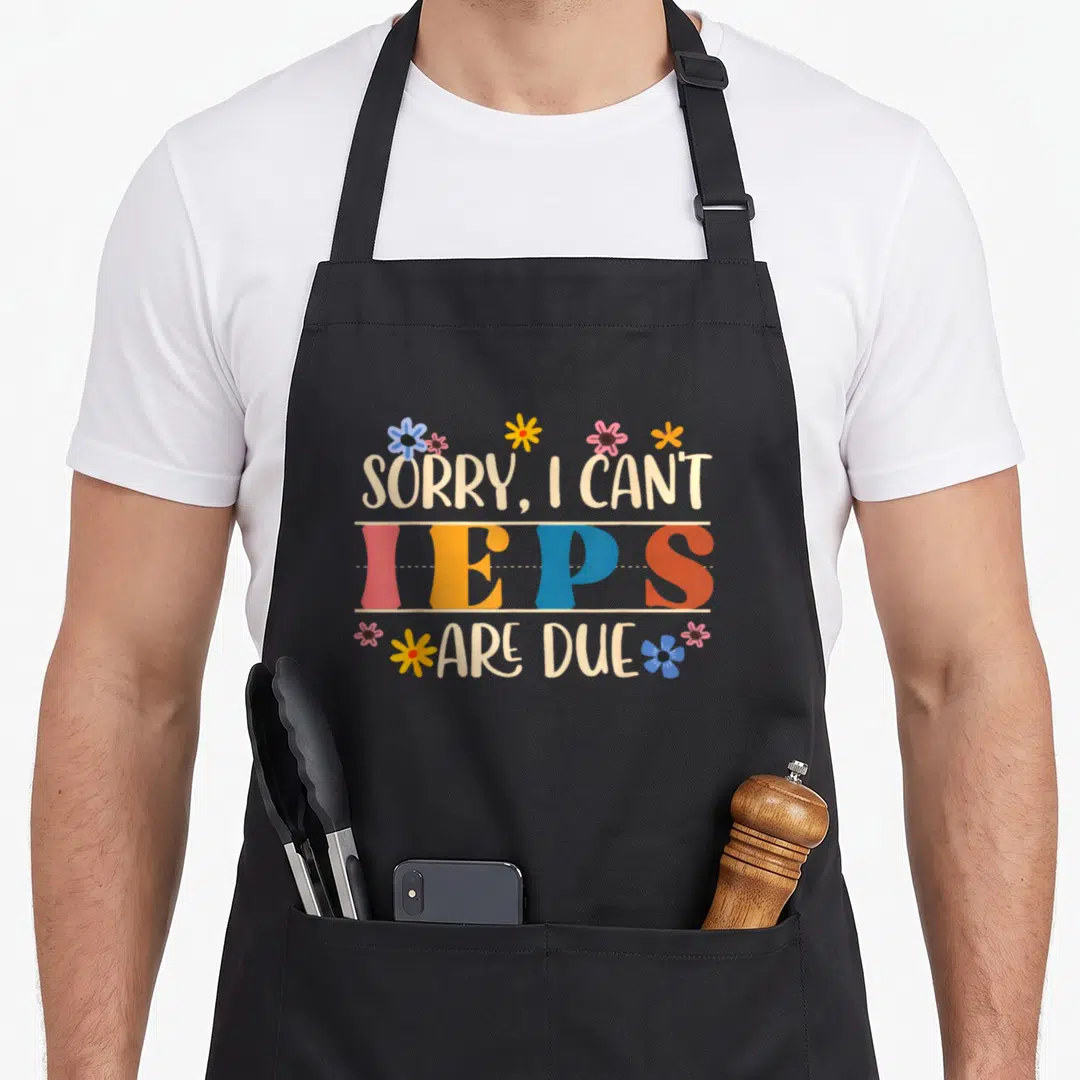 Sped teacher apron - Stacked text reading Sorry I Can't IEPS Are Due with colorful flowers and beige lettering on black — shown on a black cotton canvas apron against a white background