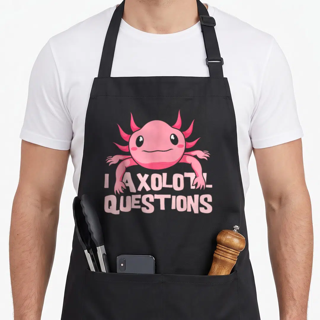 Amphibian mexican apron - Pink cartoon axolotl above two lines of text reading I AXOLOTL QUESTIONS — shown on a black cotton canvas apron against a white background