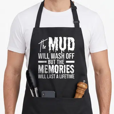 Wash mud apron - White dripping typography quote on black bib apron celebrating mudding memories — shown on a black cotton canvas apron against a white background