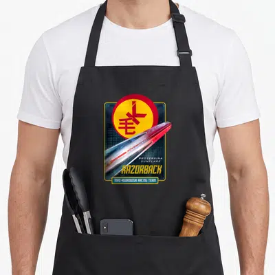 Expanse racing apron - Razorback ship and Mao-Kwikowski Racing Team text with circular emblem and stacked typography — shown on a black cotton canvas apron against a white background