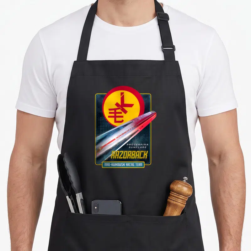 Expanse racing apron - Razorback ship and Mao-Kwikowski Racing Team text with circular emblem and stacked typography — shown on a black cotton canvas apron against a white background