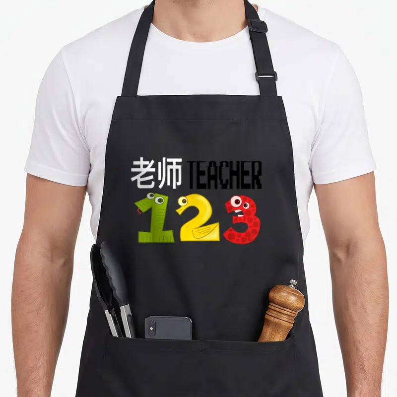 Esl teacher apron - Bilingual teacher text above green yellow red monster numbers 1 2 3 — shown on a black cotton canvas apron against a white background