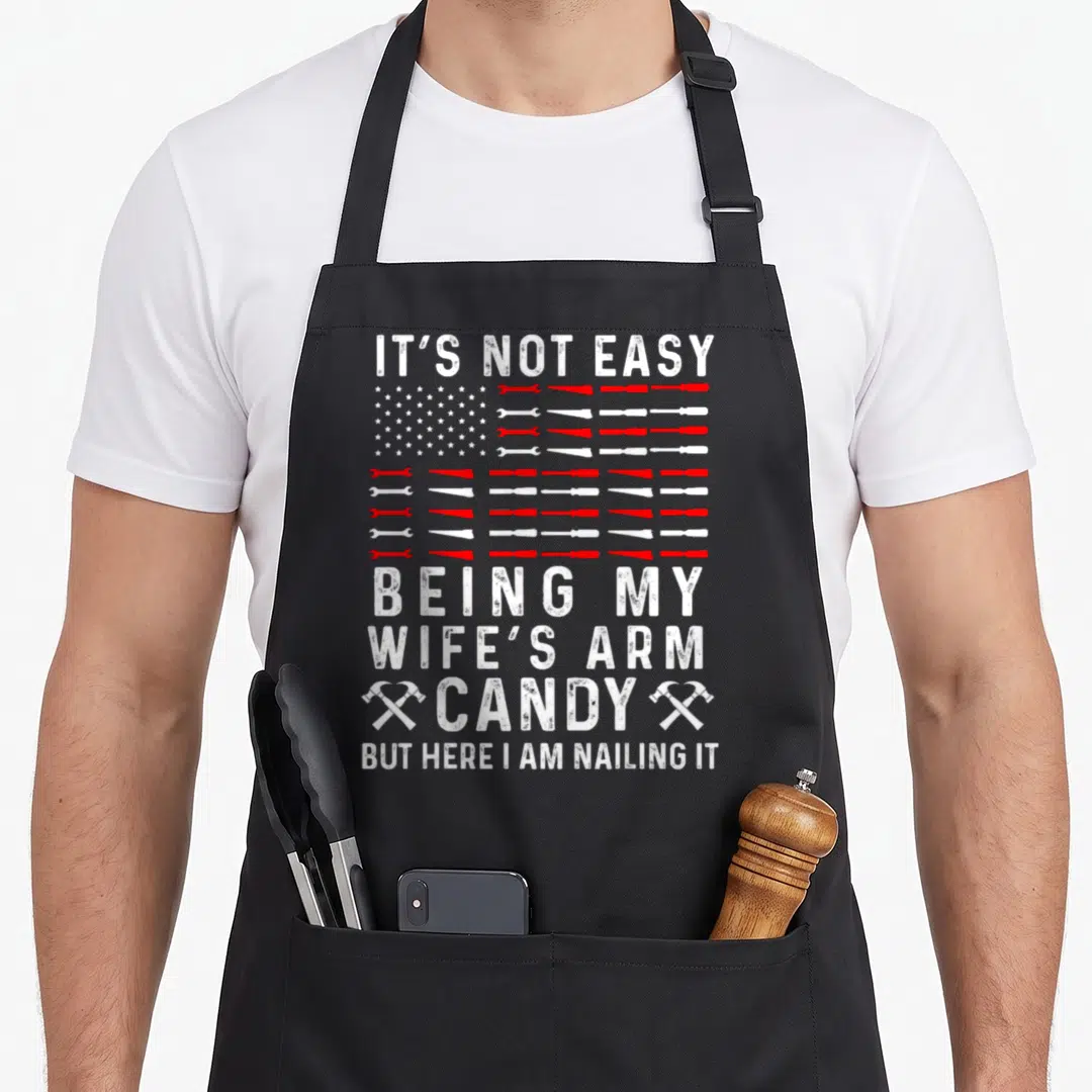 Easy wife arm father day apron - Red and white tools arranged as a flag with crossed hammers and stacked white text — shown on a black cotton canvas apron against a white background