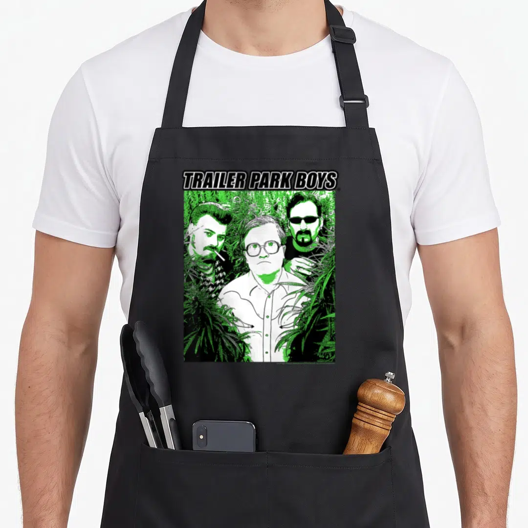 Weed trailer apron - TRAILER PARK BOYS text above three men surrounded by green cannabis leaves in black and white — shown on a black cotton canvas apron against a white background