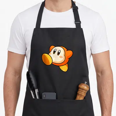 Waddle jumping dad apron - Orange and cream cartoon Kirby head centered on apron front — shown on a black cotton canvas apron against a white background