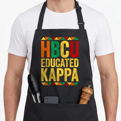History historical aprons - Stacked HBCU EDUCATED KAPPA text in orange green yellow red with triangle borders — shown on a black cotton canvas apron against a white background