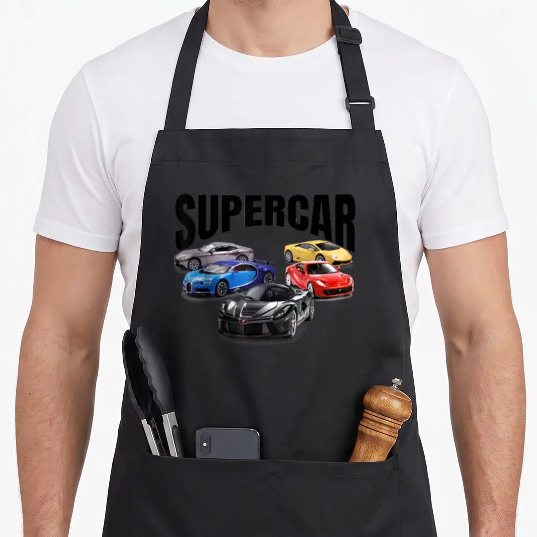 Supercar racing apron - SUPERCAR text above five red blue yellow silver and black sports cars — shown on a black cotton canvas apron against a white background