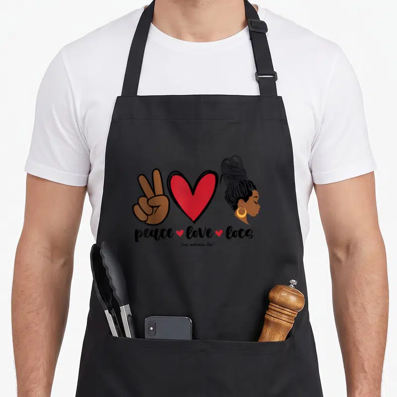 Peace business apron - Peace sign hand, red heart, woman with locs, and peace love locs text — shown on a black cotton canvas apron against a white background