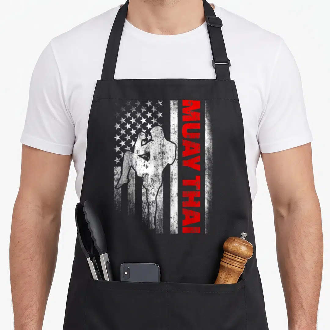 Muay american flag apron - Distressed USA flag with fighter silhouette and vertical MUAY THAI text in red white blue — shown on a black cotton canvas apron against a white background
